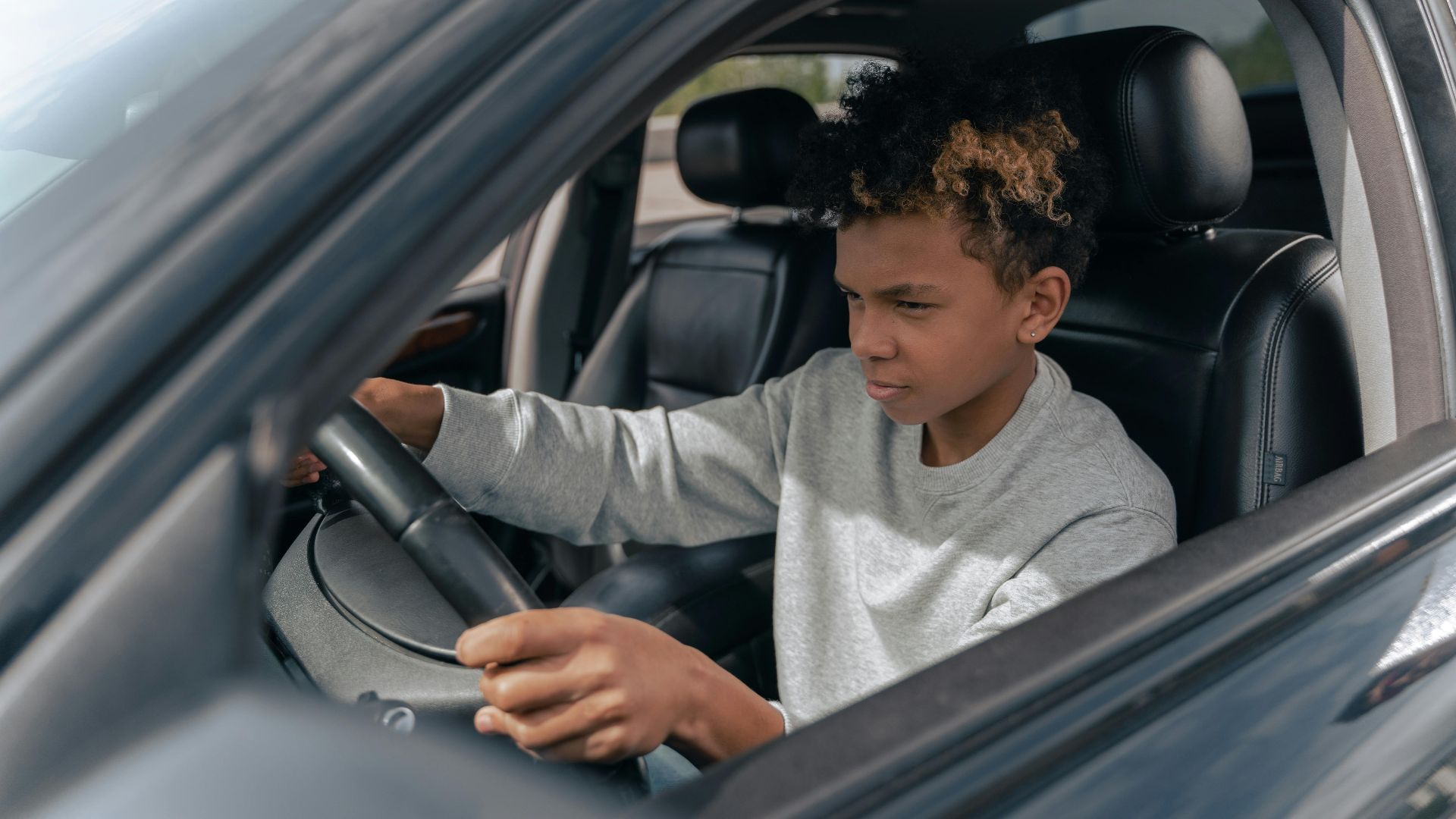 Teen boy learning to drive a car with focus and determination.