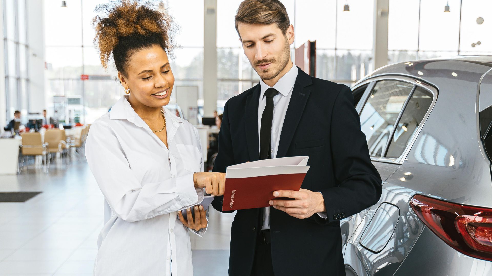 Man and woman discussing car purchase inside a modern dealership.