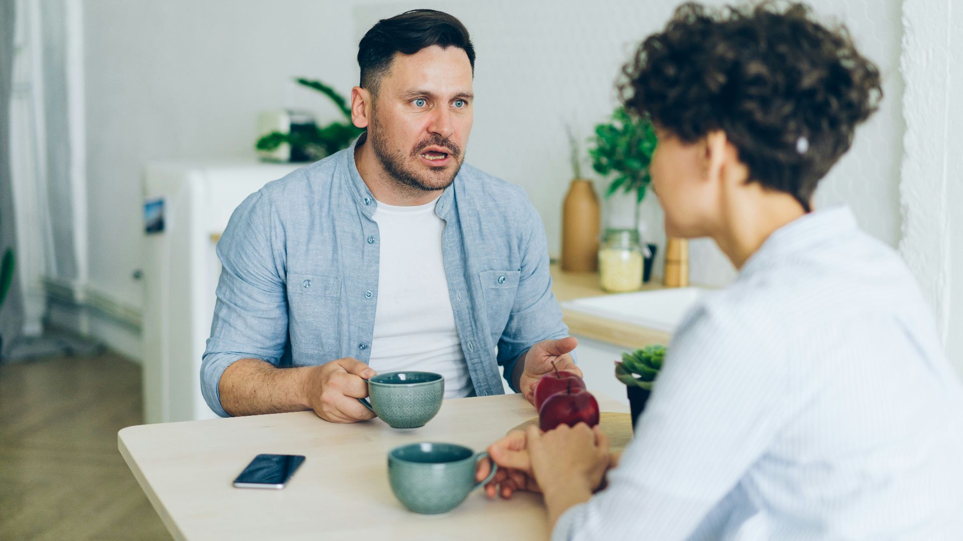 a man sitting at a table talking to a woman