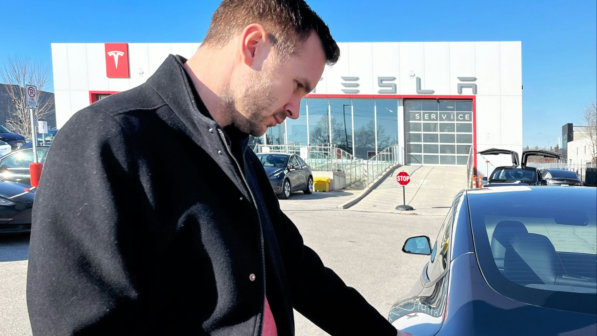 a man standing next to a car in a parking lot