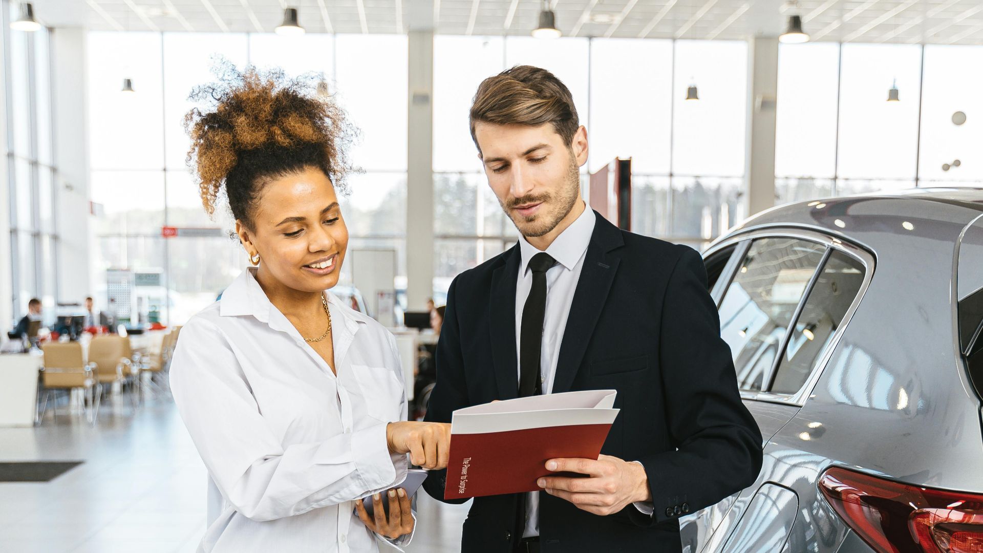 Man and woman discussing car purchase inside a modern dealership.