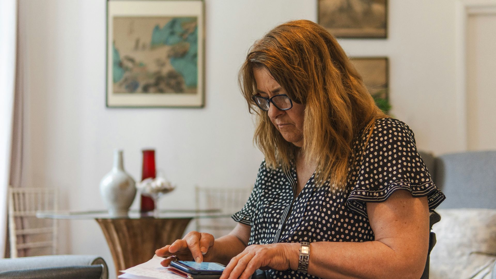 Woman looking at phone while writing on paper