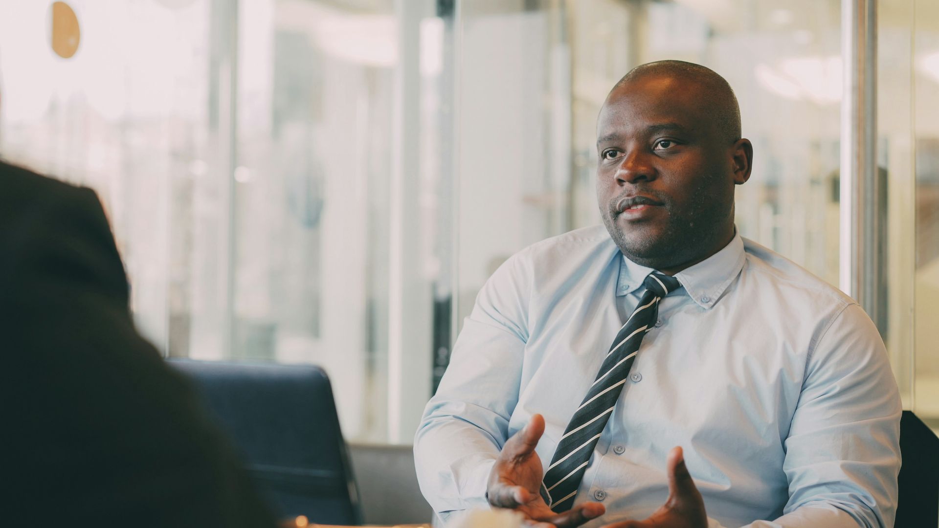 Man in a light blue shirt and tie talking.
