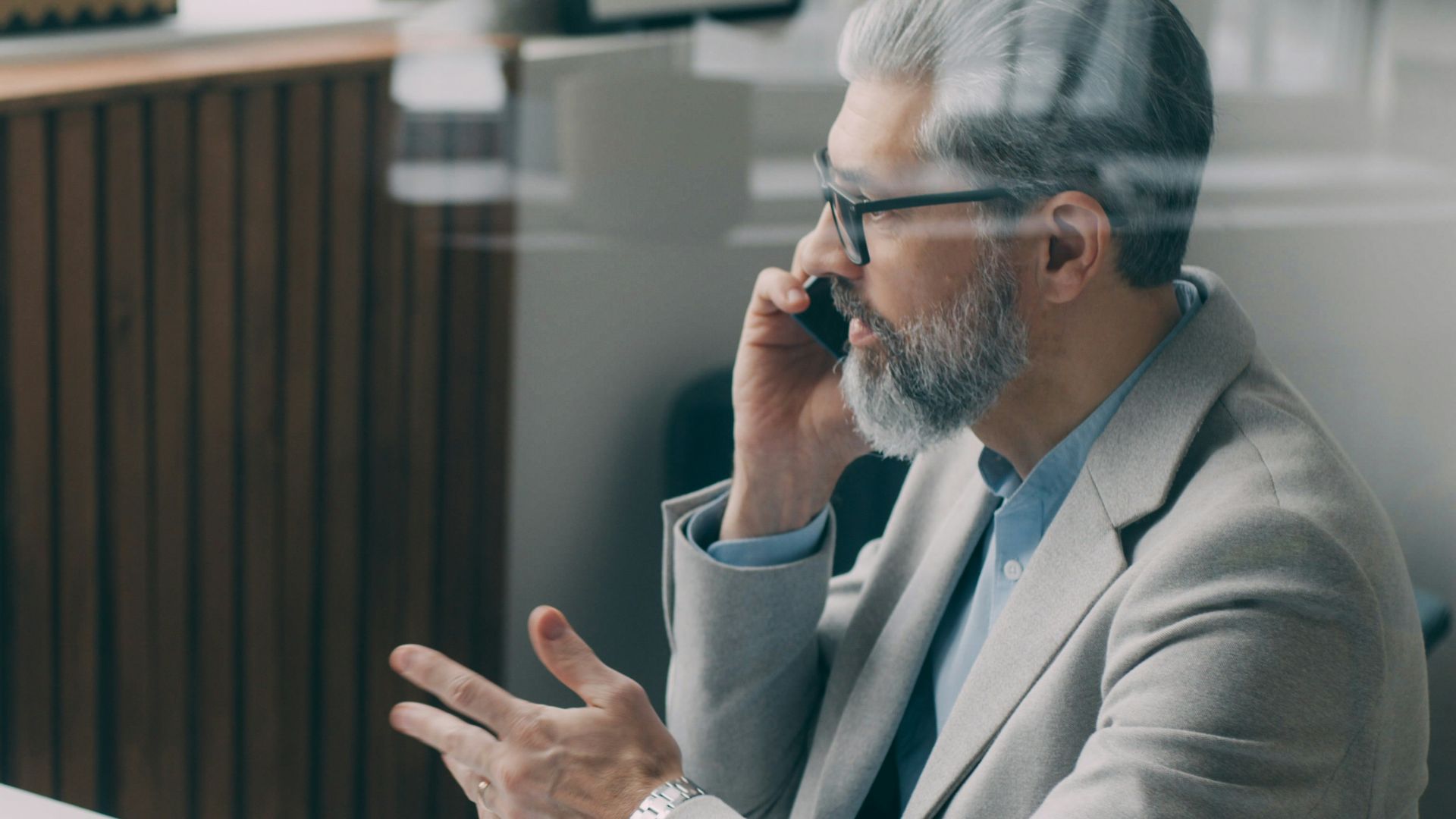 A man sitting at a desk talking on a cell phone