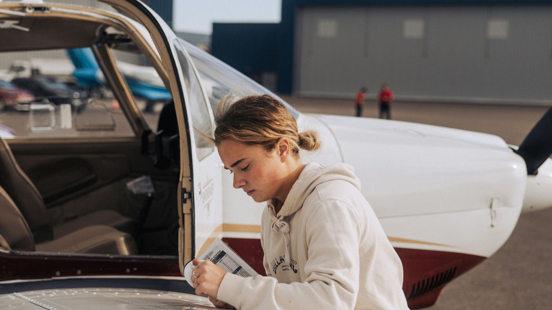 Young woman checking checklist by small airplane