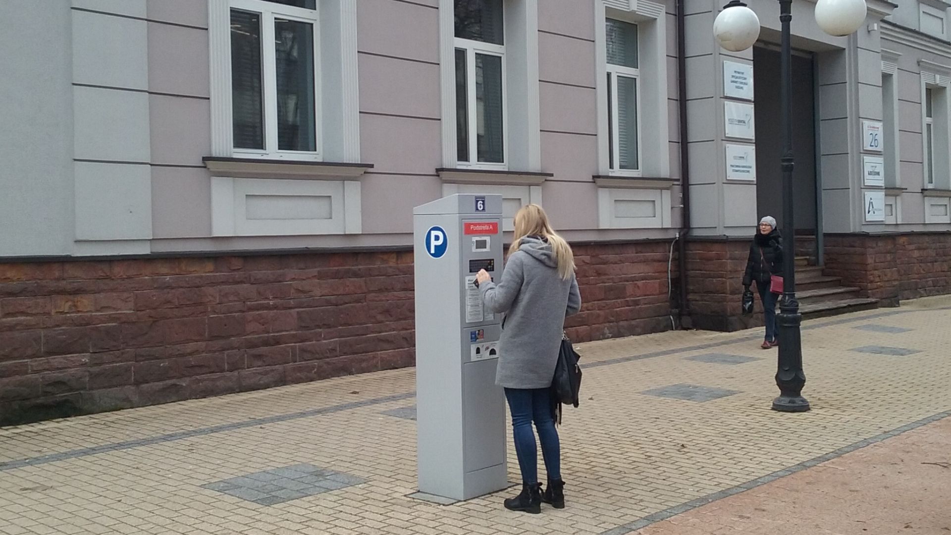A girl with Solar parking meter near Koral Family Palace in Tomaszow Mazowiecki, Poland, EU
