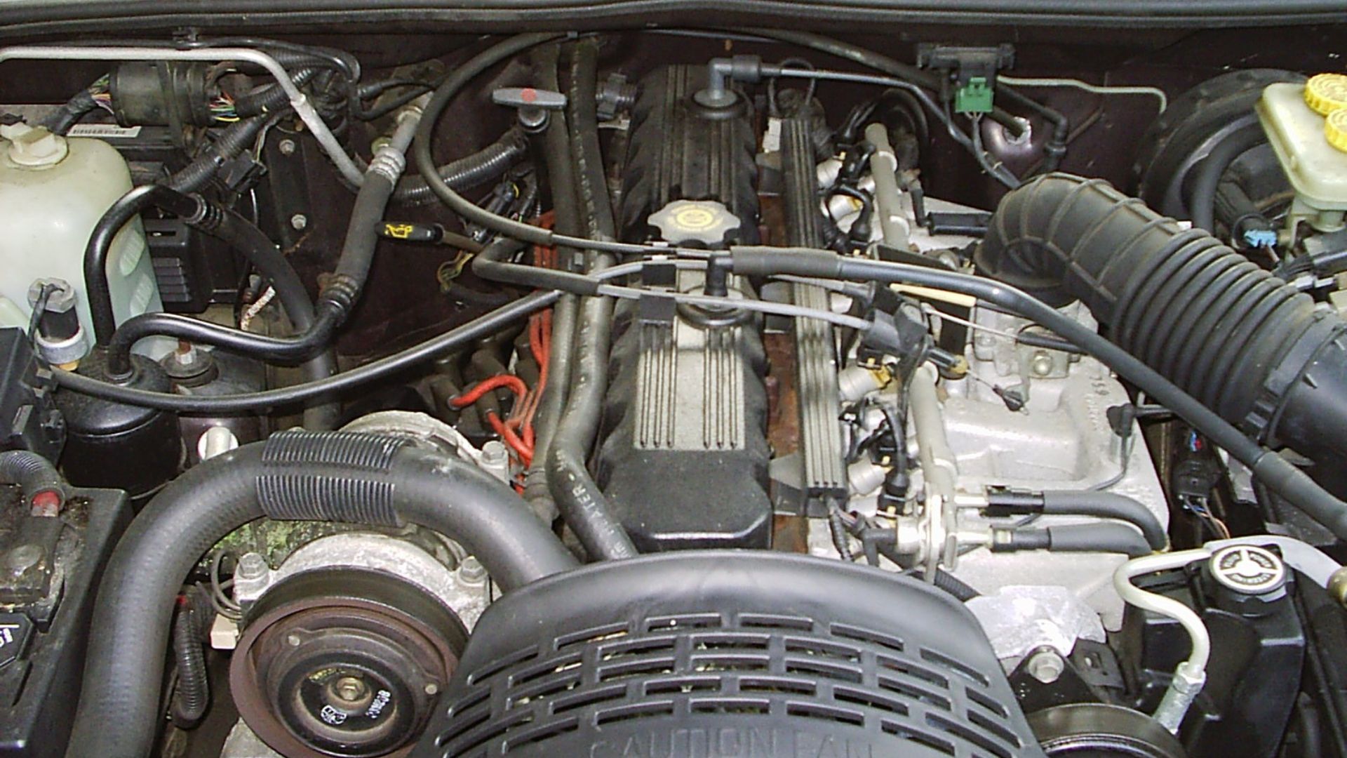 The engine (4.0 liter straight-six) bay of a 1993 Jeep Grand Cherokee (ZJ). This luxurious sport utility (SUV) is finished in Metallic Blackberry (paint code: PM9), a deep burgundy. Equipment includes the Laredo 26F package and the Quadra-Trac full-time system. This is an early production ZJ model that was built in April 1992.
