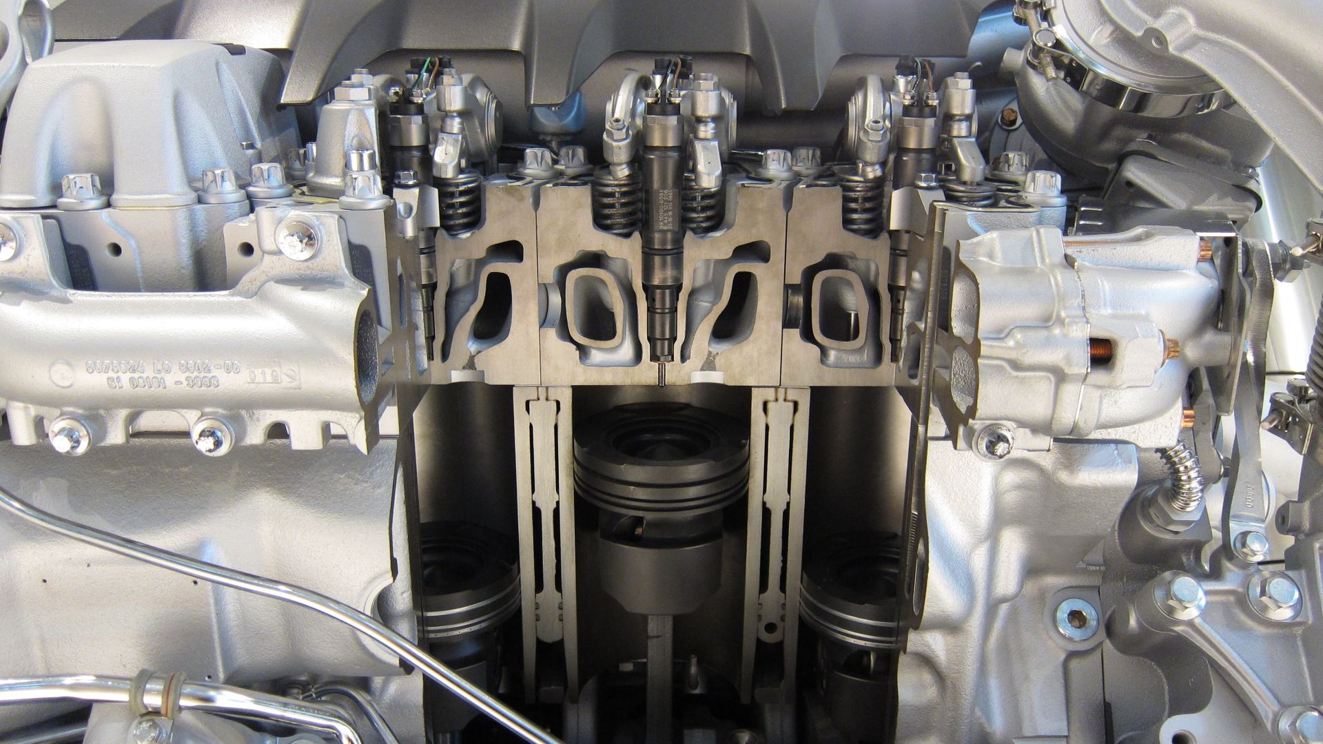A cutaway of a V8 Diesel engine from a MAN TGX. Three pistons and their cylinders are visible, with their respective common rail diesel fuel injectors.
The engine is reported to output 680hp and 3000 Nm, and is displayed at the Deutsches Museum.