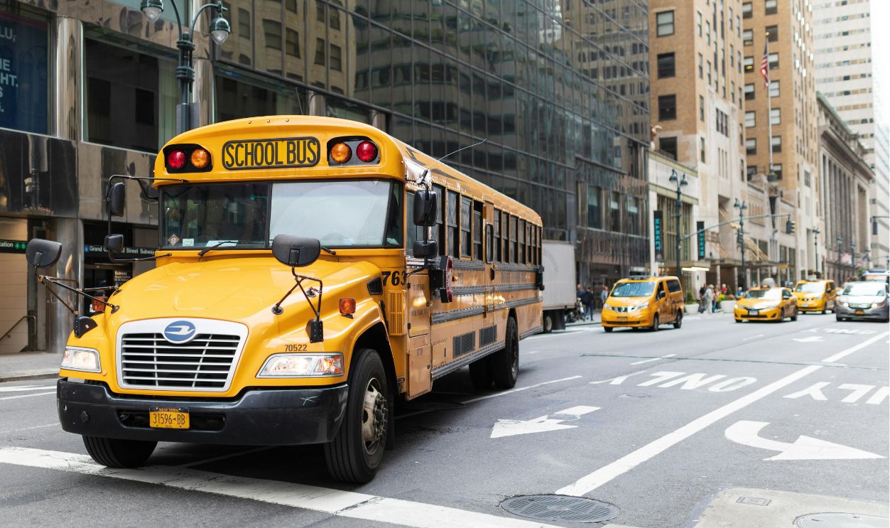 A yellow school bus navigates a busy New York City street  