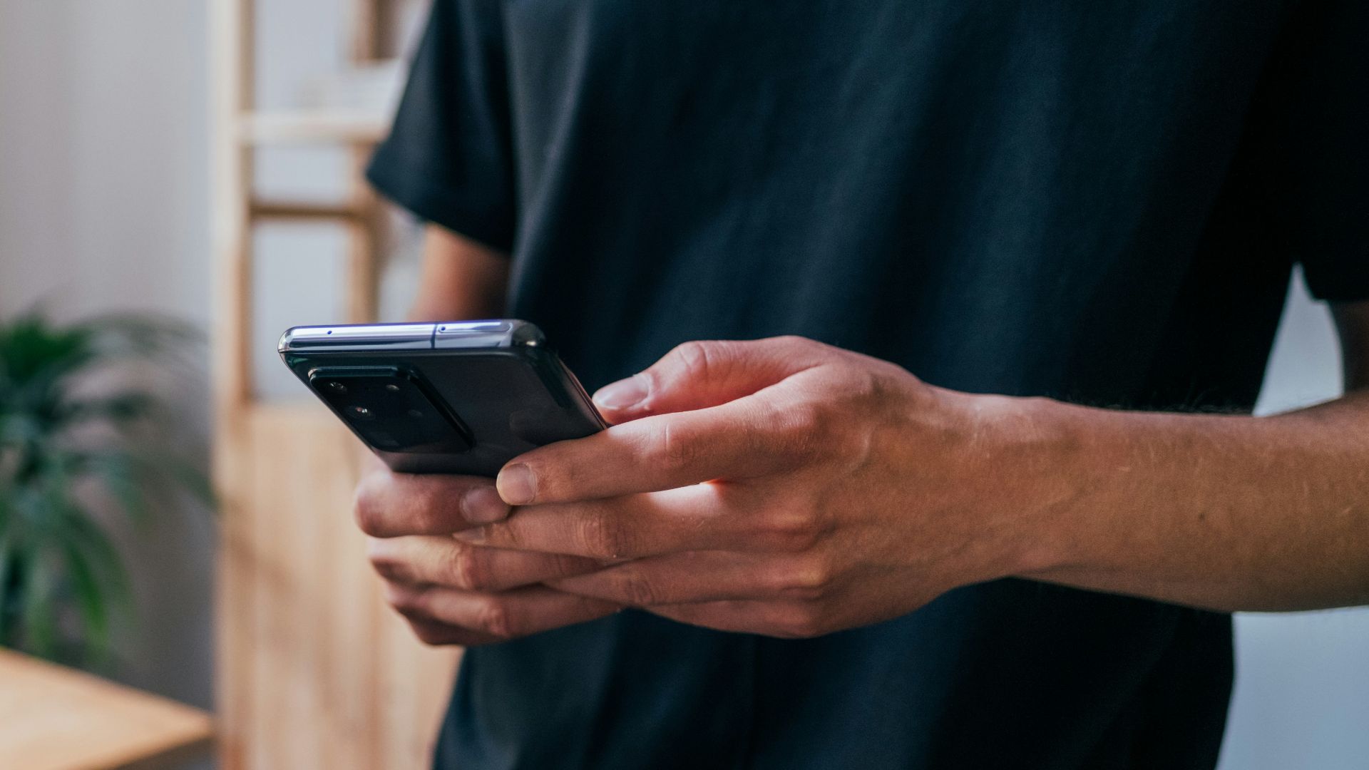 person in blue long sleeve shirt holding black smartphone