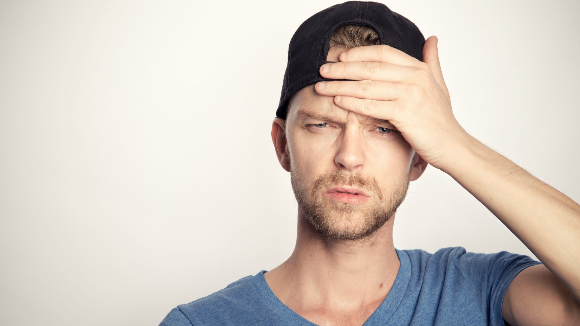man in blue crew neck shirt covering his face