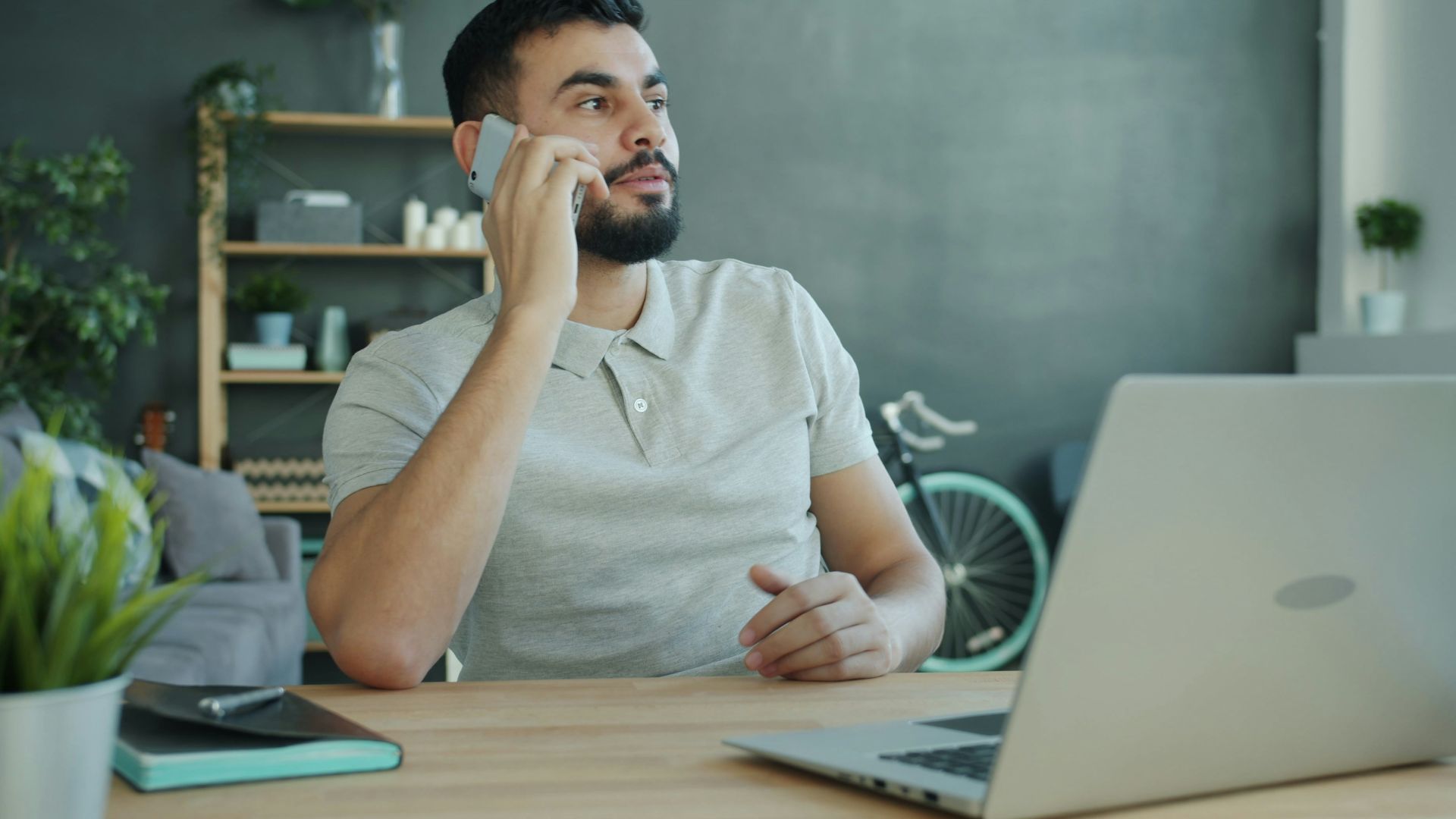 Man talking on phone at desk with laptop.