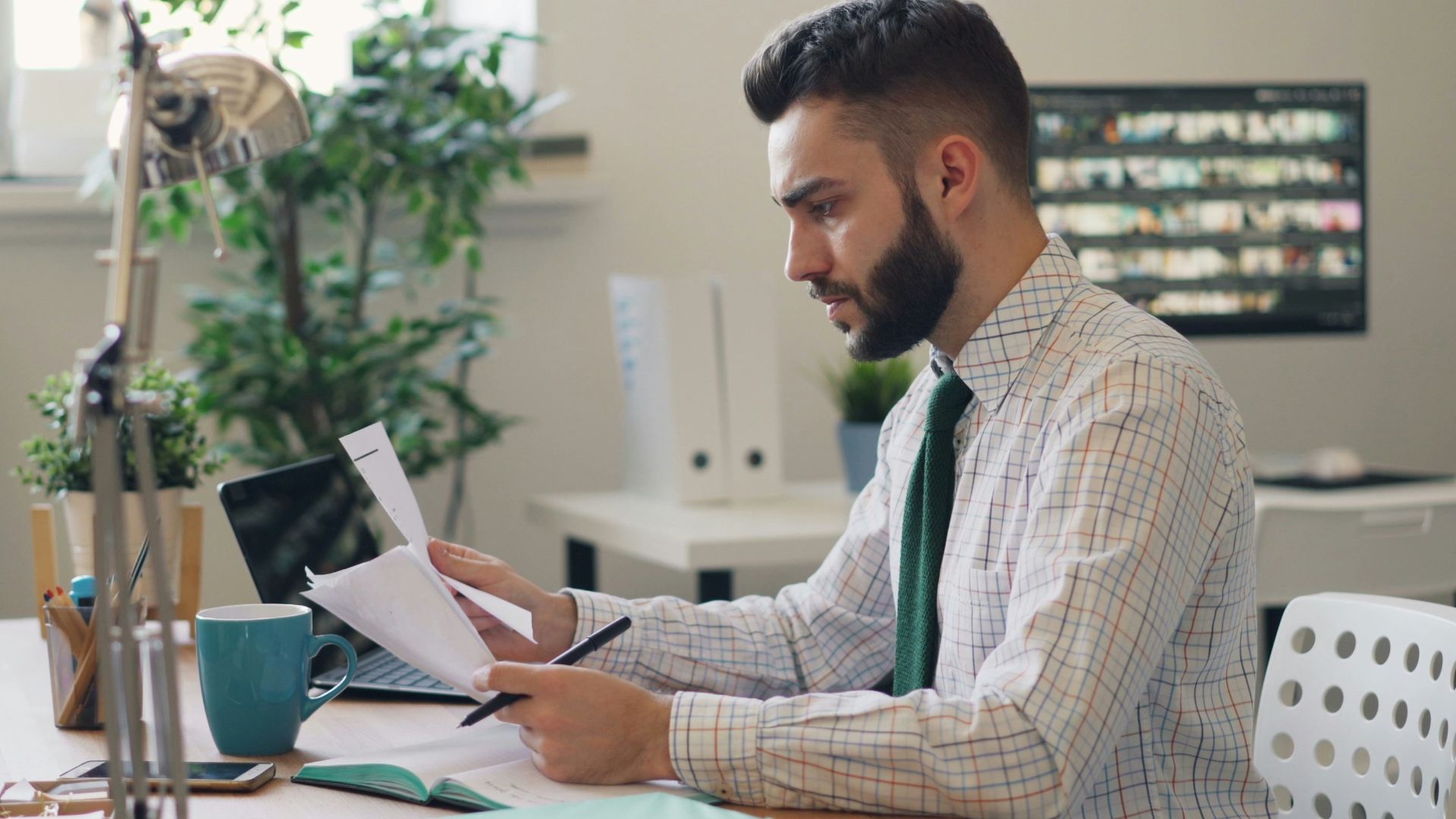 a man sitting at a desk with a laptop and papers