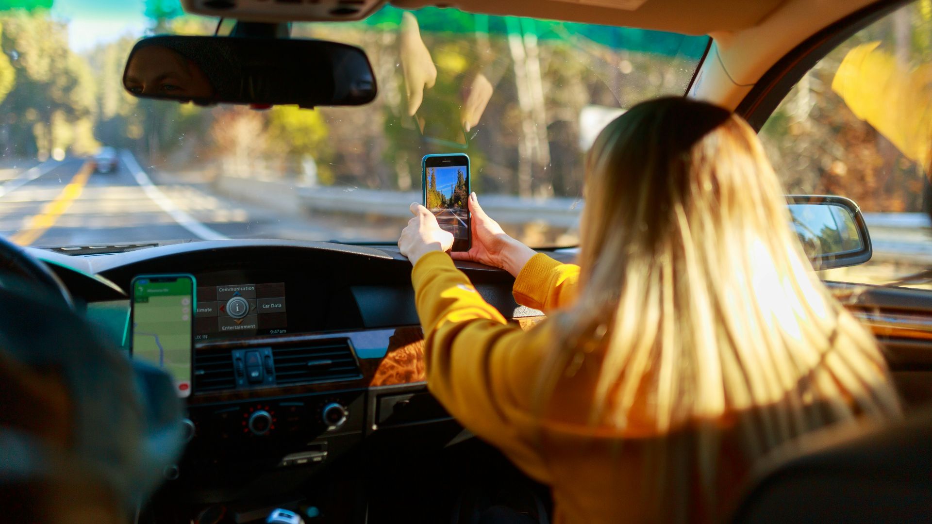 a woman driving a car with a cell phone in her hand