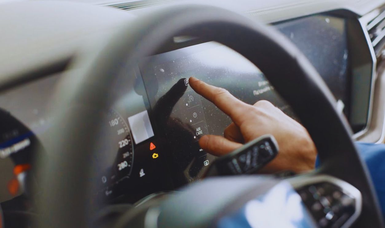 Close-up of a hand interacting with a car's digital dashboard. Modern technology and driving interface