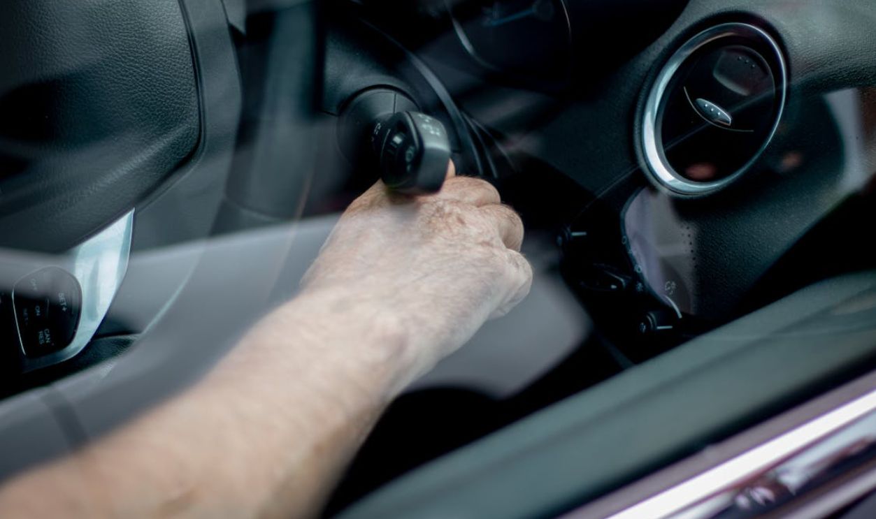 Close-up of a driver's hand starting the car ignition in Leeds, UK
