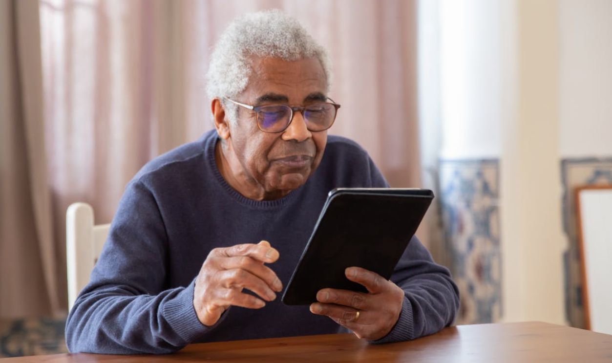 Senior man using a digital tablet indoors, focusing on modern technology and connection