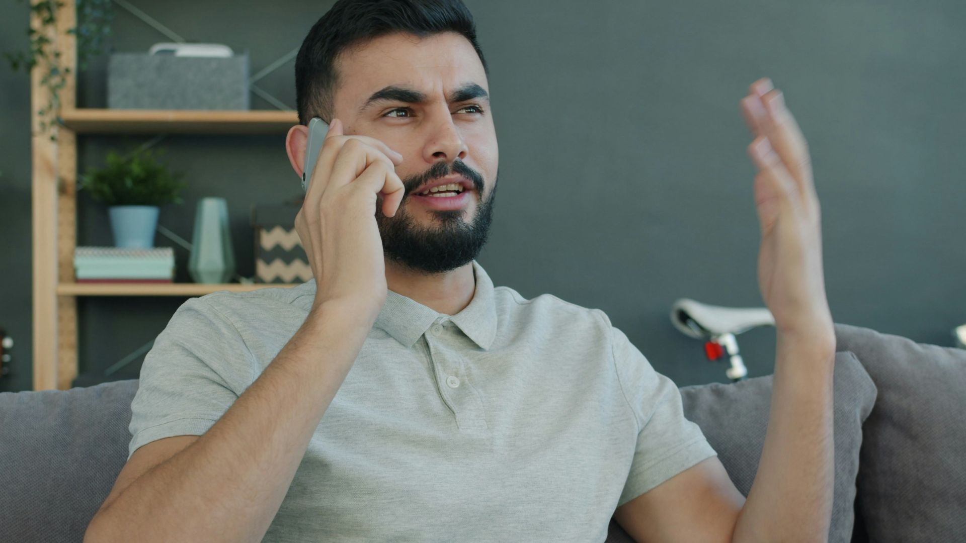 Man talking animatedly on the phone while sitting on couch.