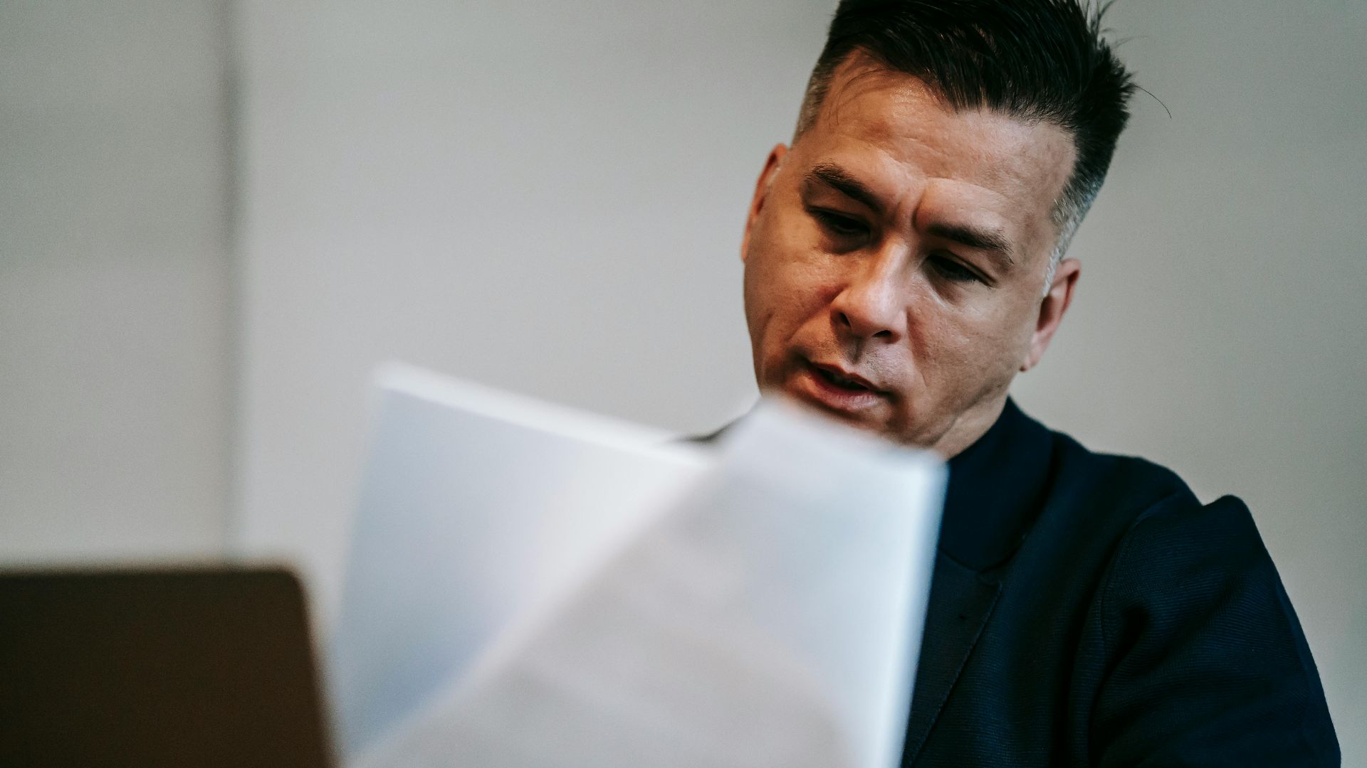 Professional man intently reviewing paperwork at his workstation indoors.