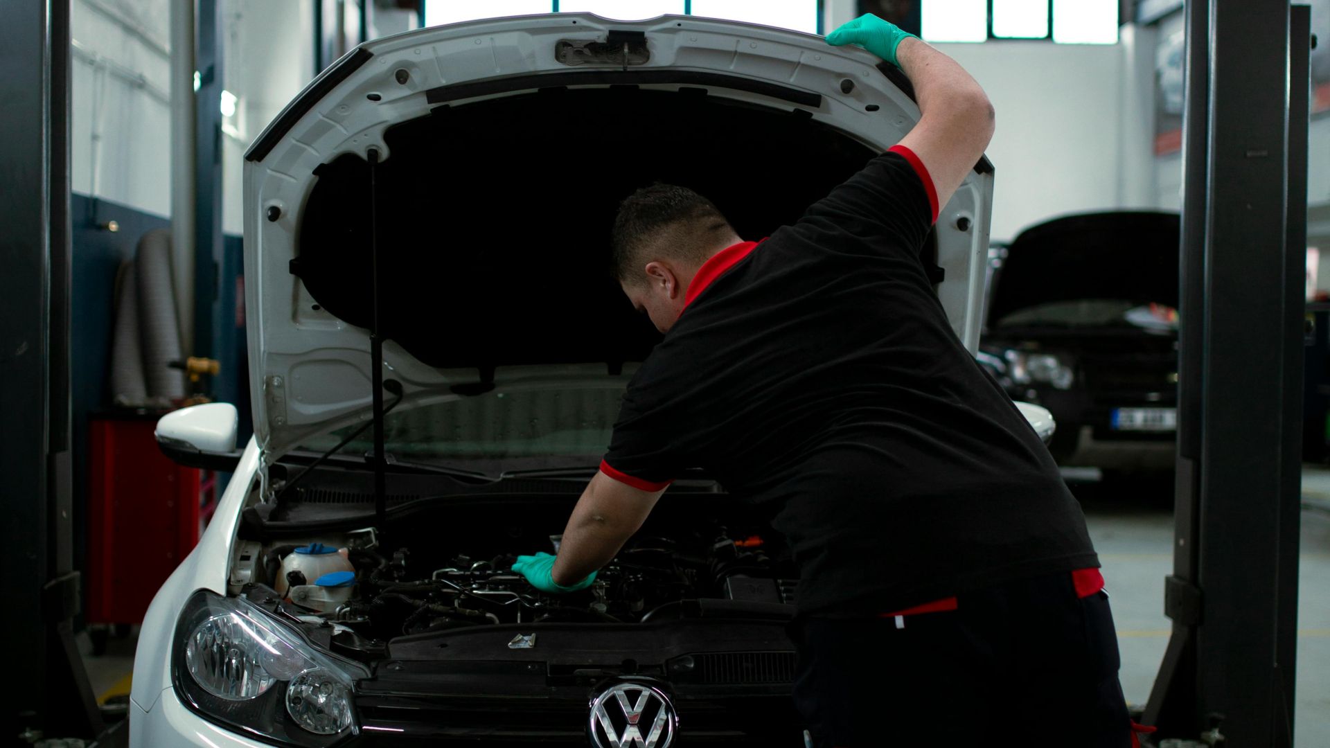 A mechanic works on a Volkswagen engine in an indoor garage setting, showcasing automotive repair skills.