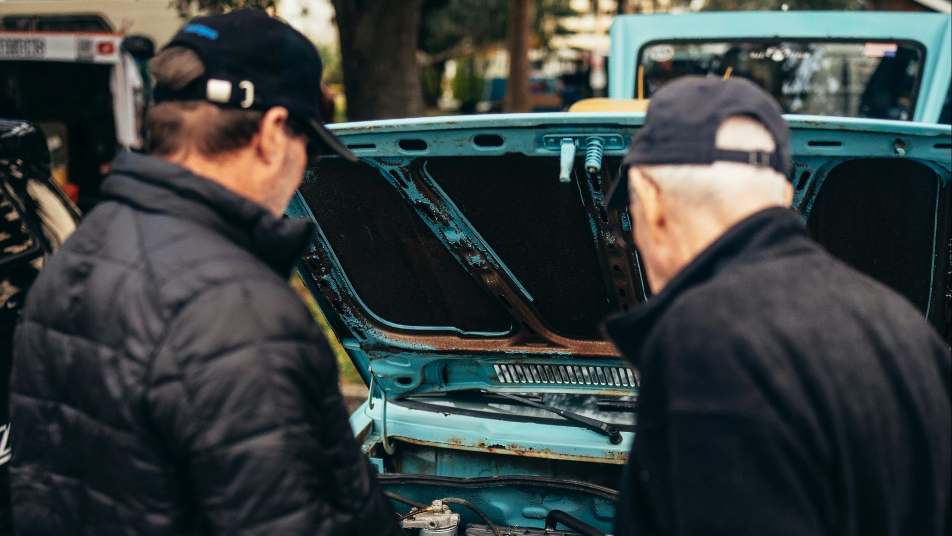 Two men observe a vintage Volkswagen with open hood at a car show. Perfect for automotive enthusiasts.