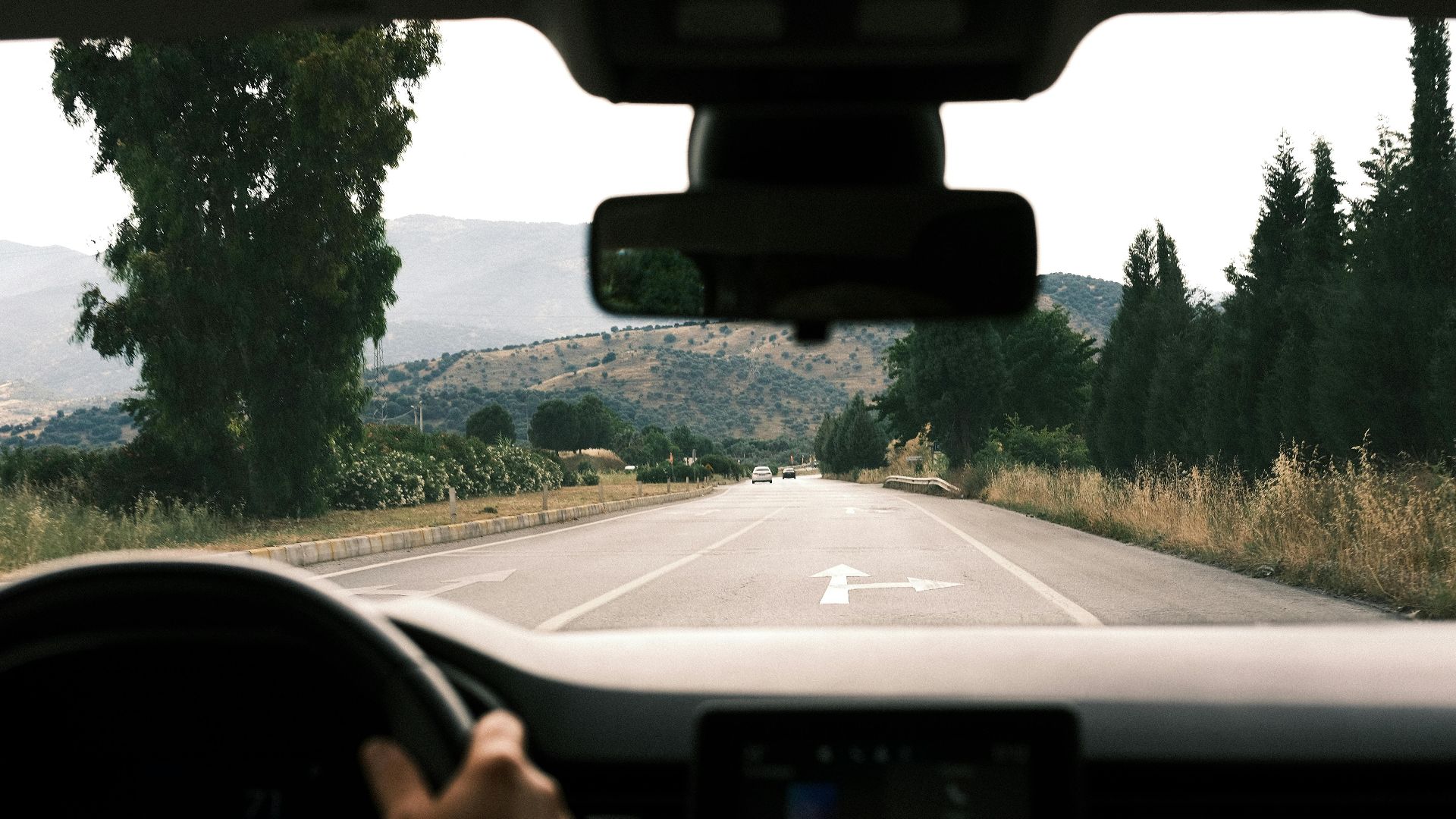 View from inside a car driving on a scenic, mountainous road during daytime.