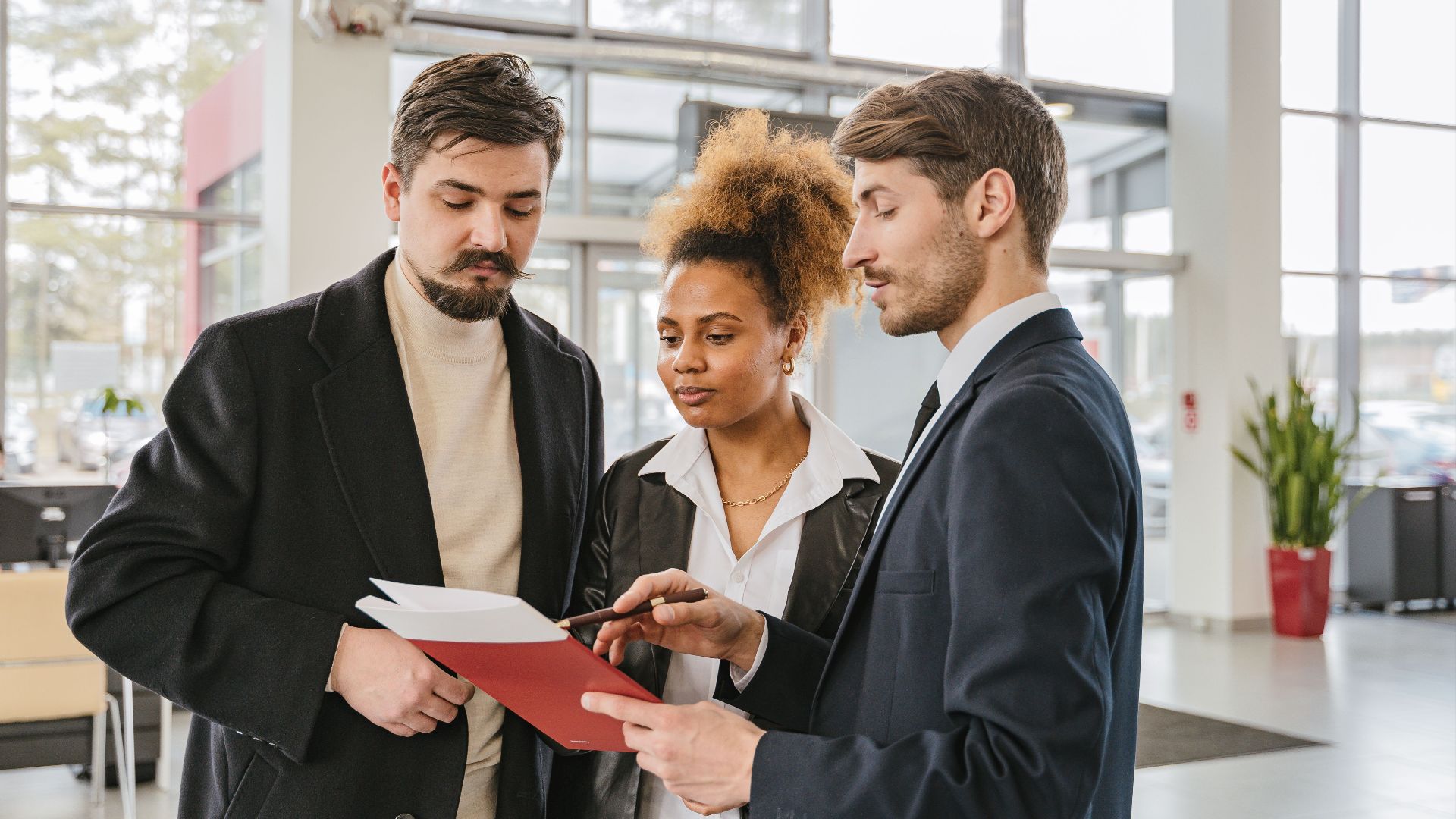 Three professionals discuss documents in a modern office setting, highlighting teamwork and collaboration.