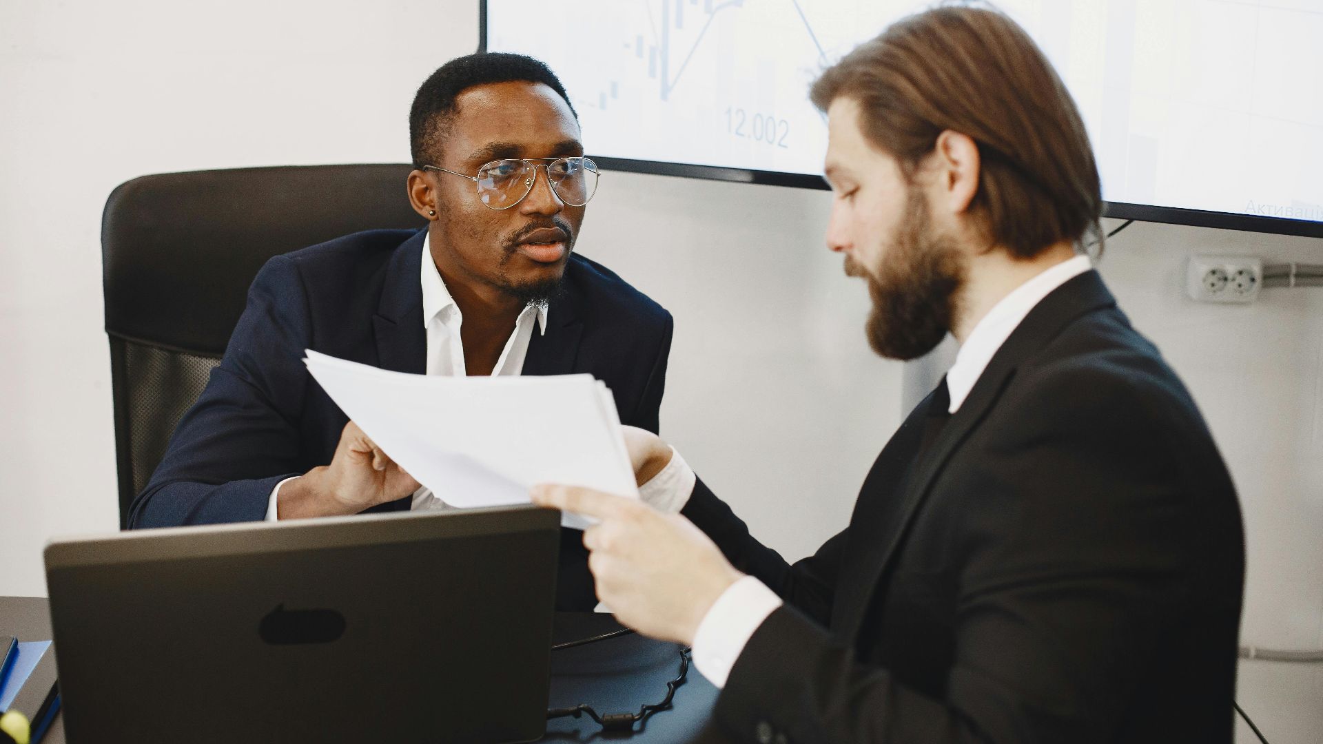 Professionals examining documents in an office business meeting setup.