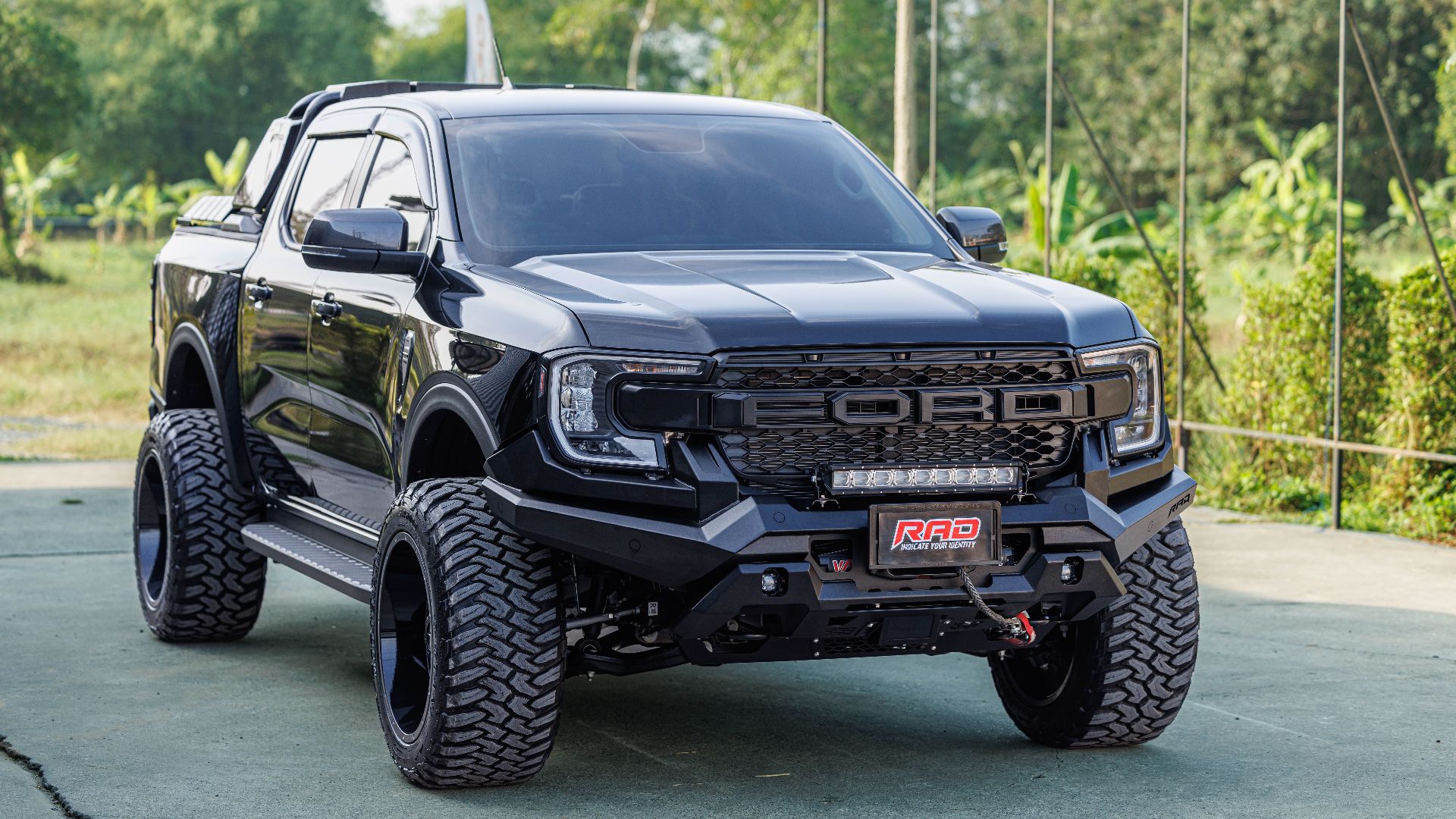 A robust black pickup truck with large tires and unique design parked outdoors on a clear day.