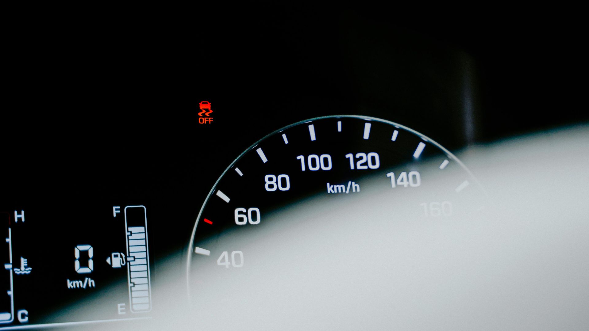 Detailed close-up of a car speedometer displaying a digital reading and warning light.
