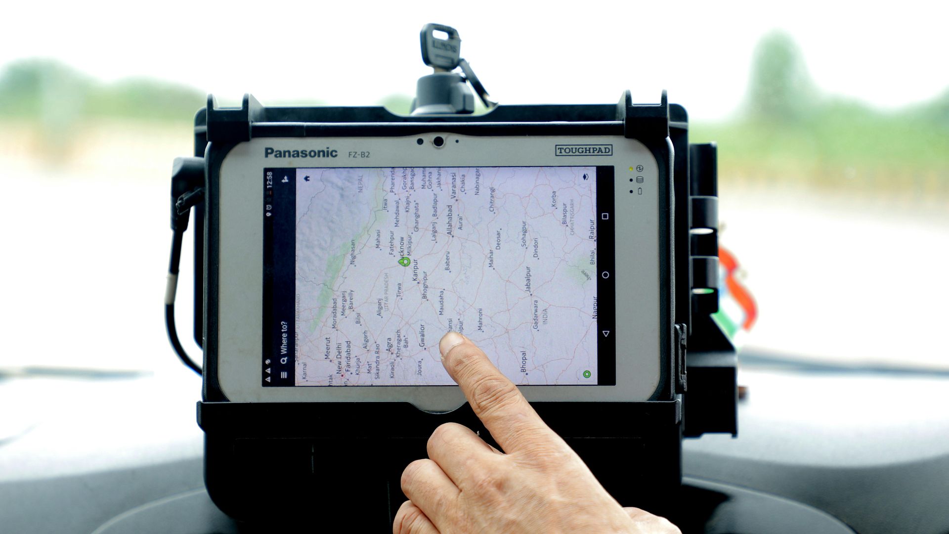 Close-up of hand interacting with GPS navigation on a car-mounted tablet screen, showcasing modern technology.