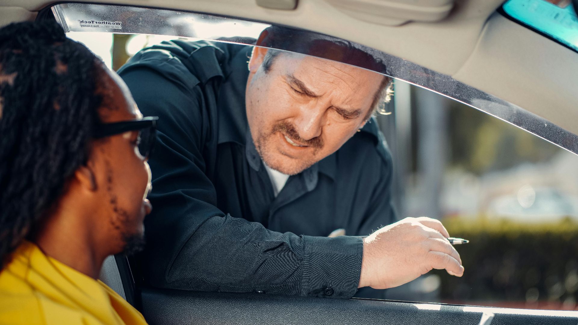 A police officer interacts with a driver through a car window, emphasizing law enforcement and public safety.