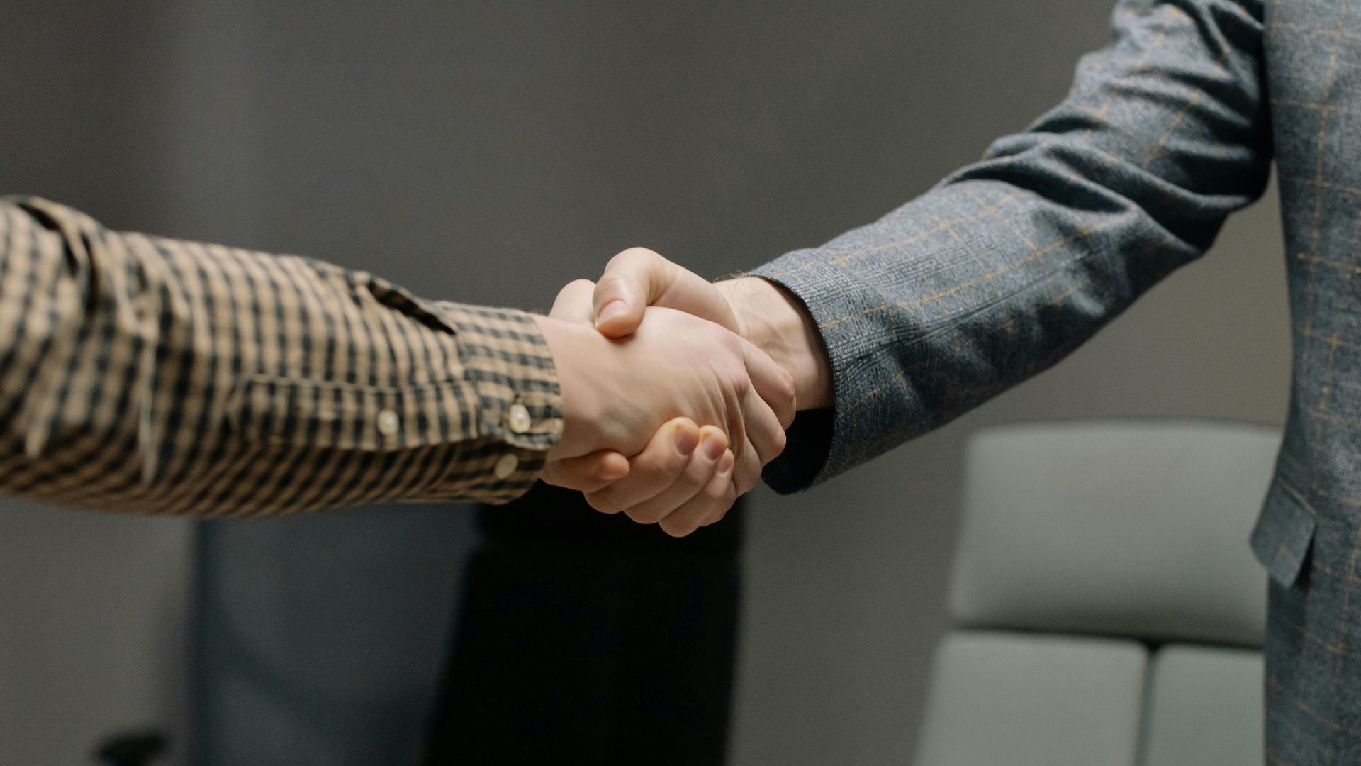 Close-up of two professionals shaking hands in an office, symbolizing successful business dealings.