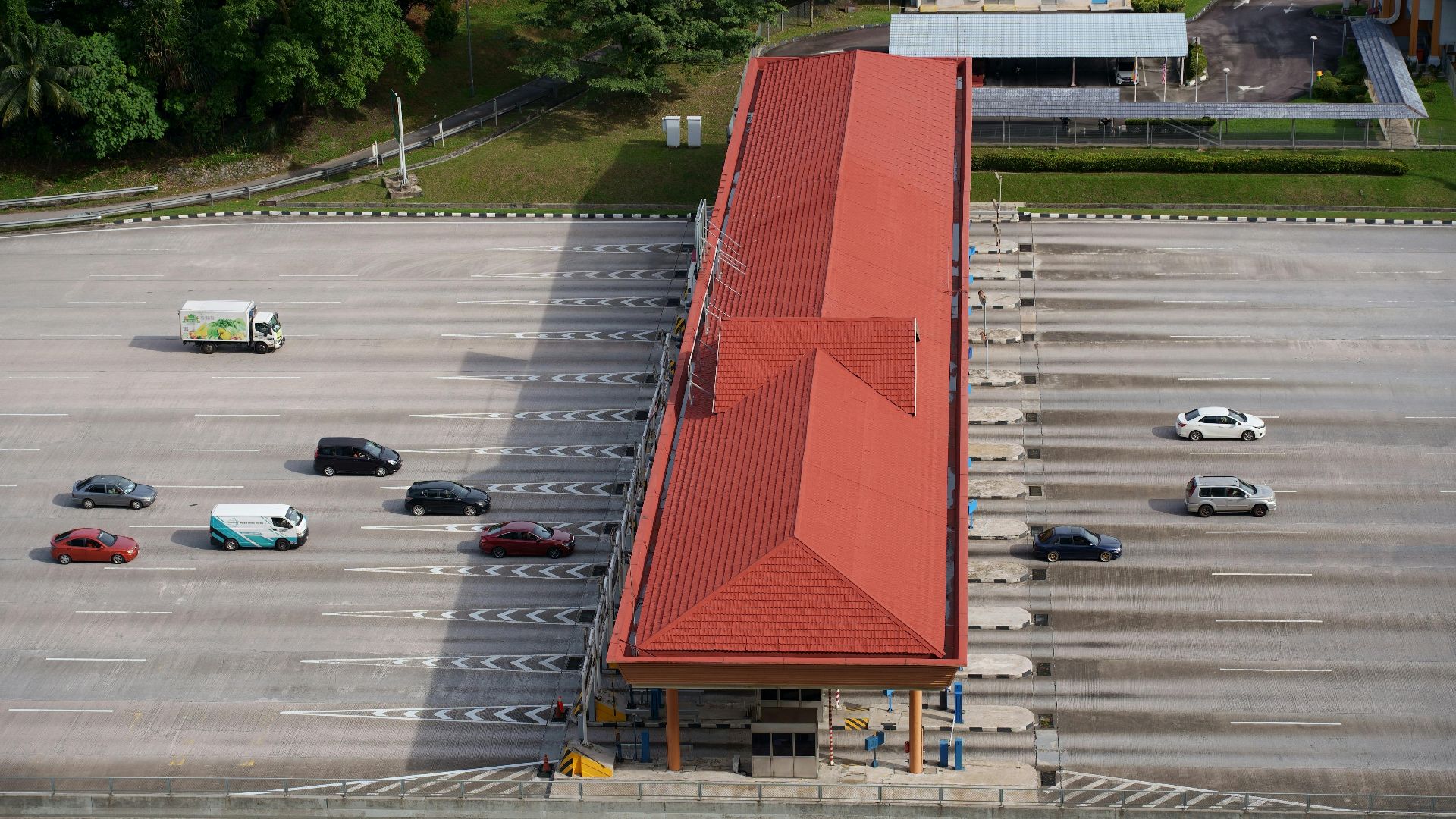 High angle aerial shot of a toll plaza with cars and trucks on an expansive highway.