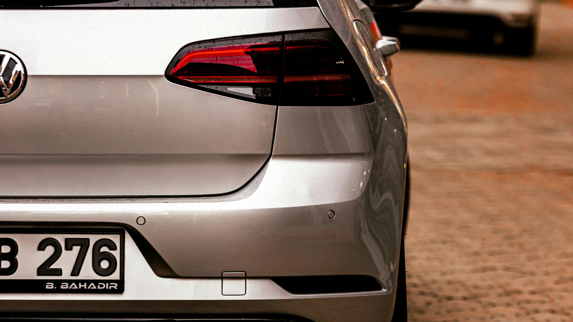 A silver car with visible taillights parked on a city street.