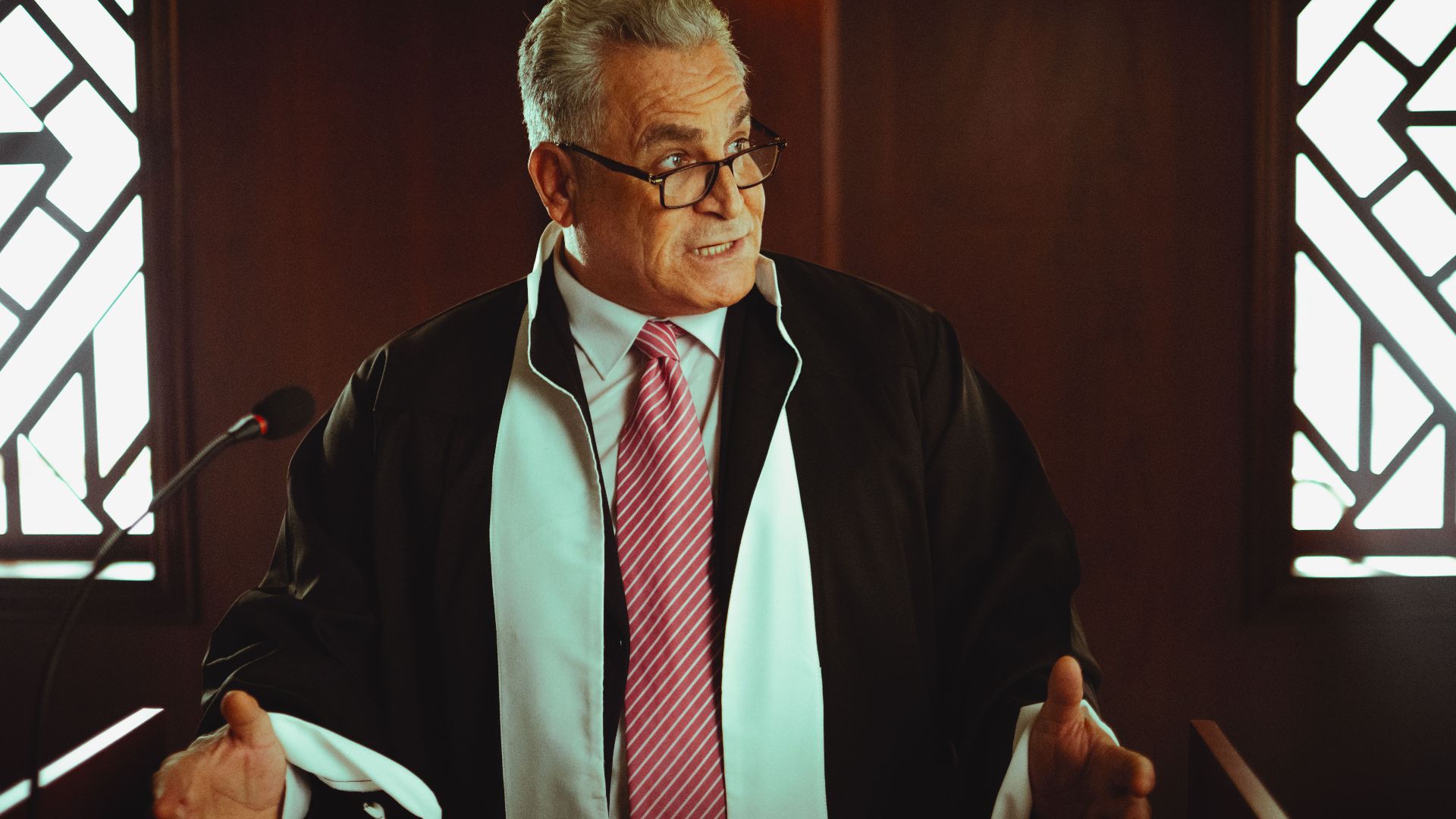 Senior male lawyer presenting a case in a Baghdad courtroom, wearing a classic black robe.