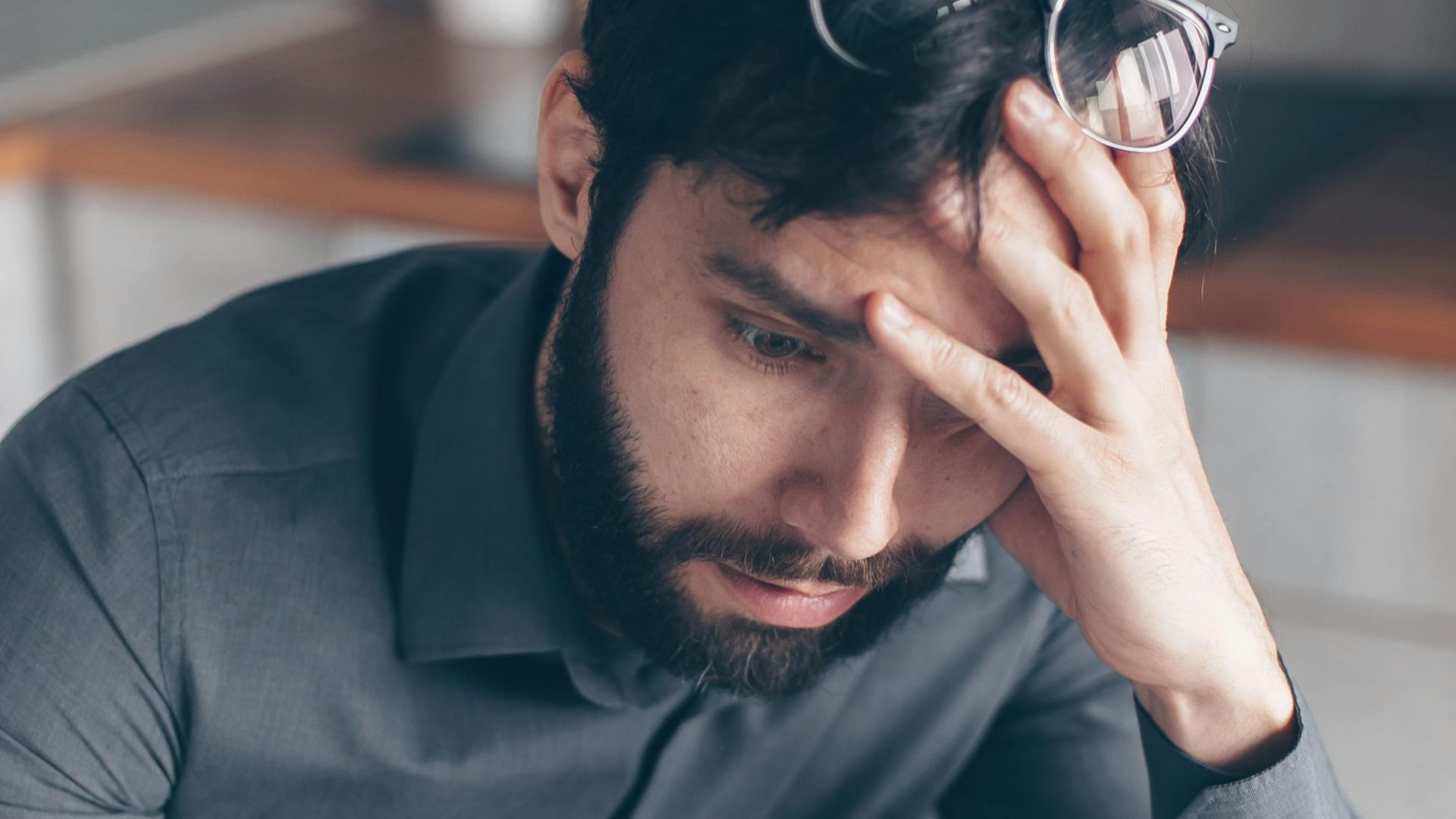 Man with eyeglasses on head looks worried as he reads paperwork, expressing concern.