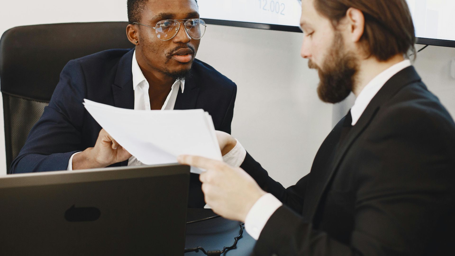 Professionals examining documents in an office business meeting setup.