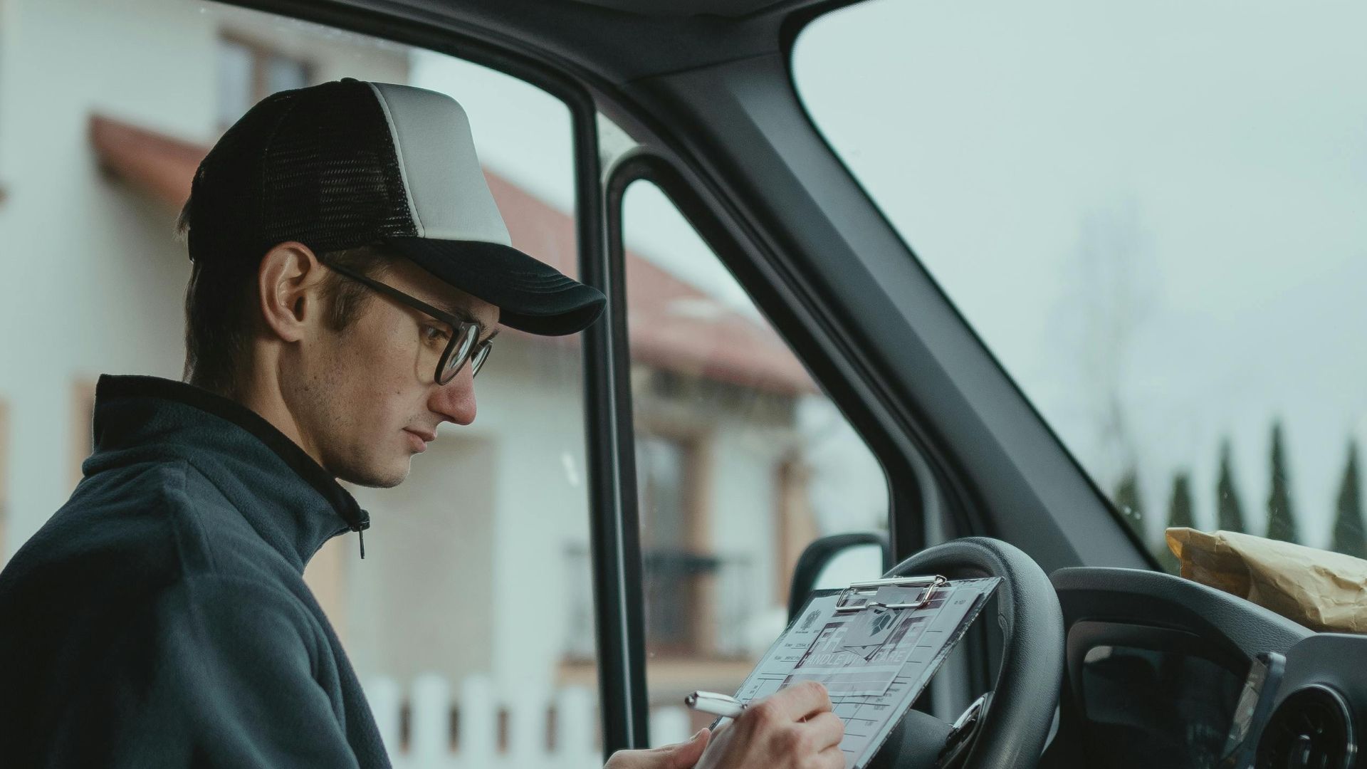 Delivery driver checks clipboard in van, preparing packages for delivery.