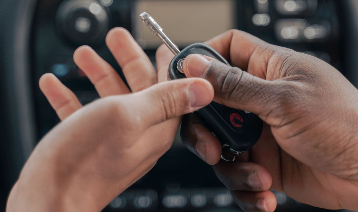 Two people exchanging car keys inside a luxury car, emphasizing guidance and learning.
