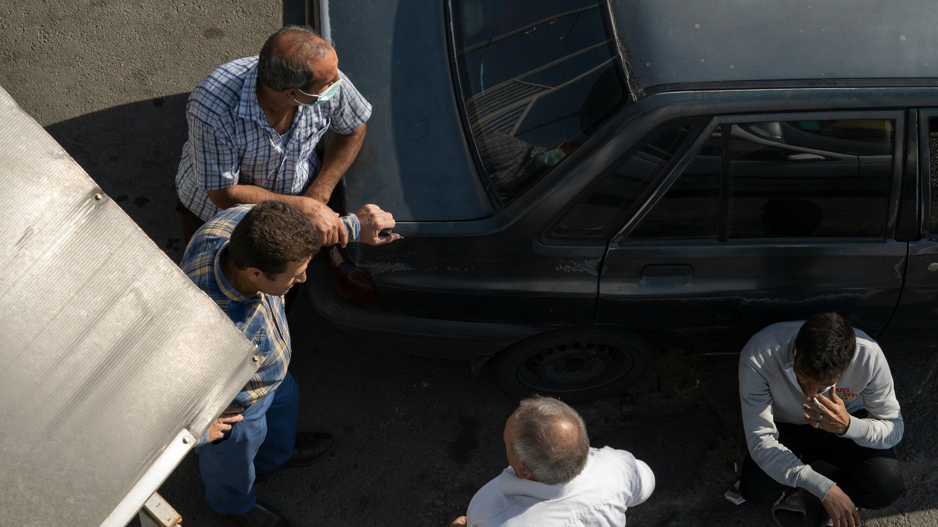 a group of men standing around a car