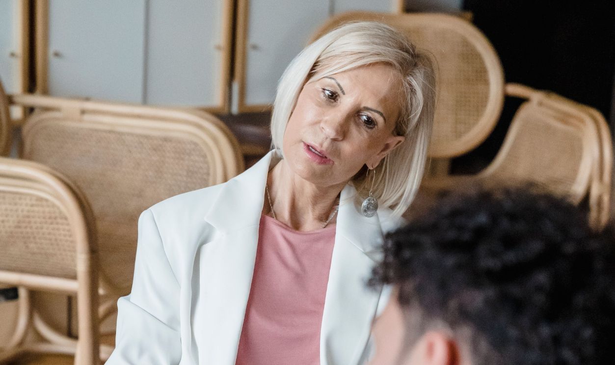 A therapist listens attentively while taking notes during a counseling session with a client