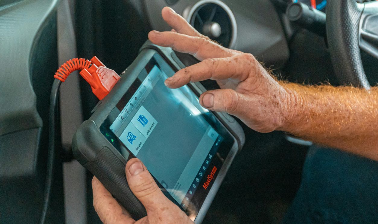 Mechanic using a diagnostic tool inside a car to check for engine issues and ensure proper maintenance