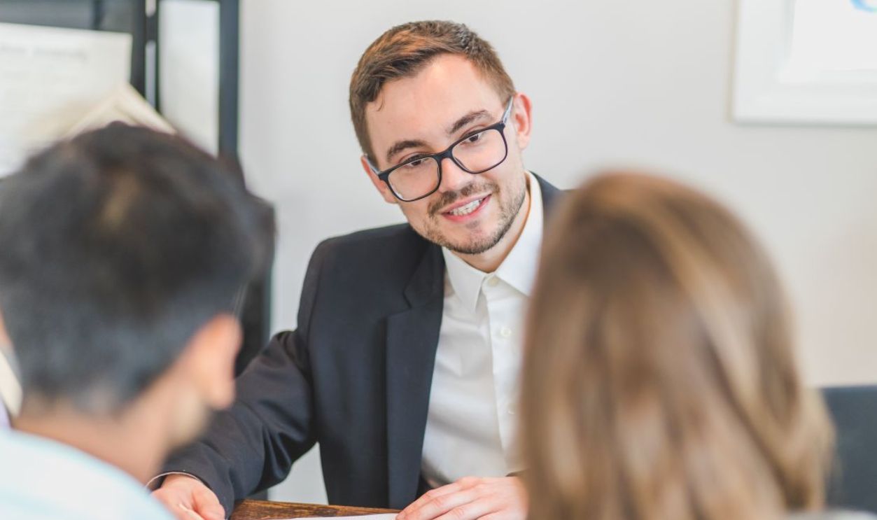 Smiling businessman in a suit and eyeglasses during a team discussion