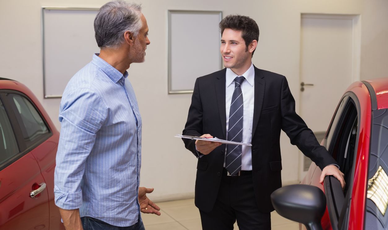 Shutterstock-254335069, Smiling businessman speaking with his customer at new car showroom