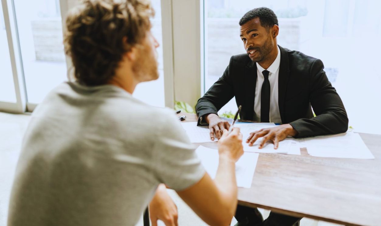 Two men having a discussion over documents in a modern office setting.