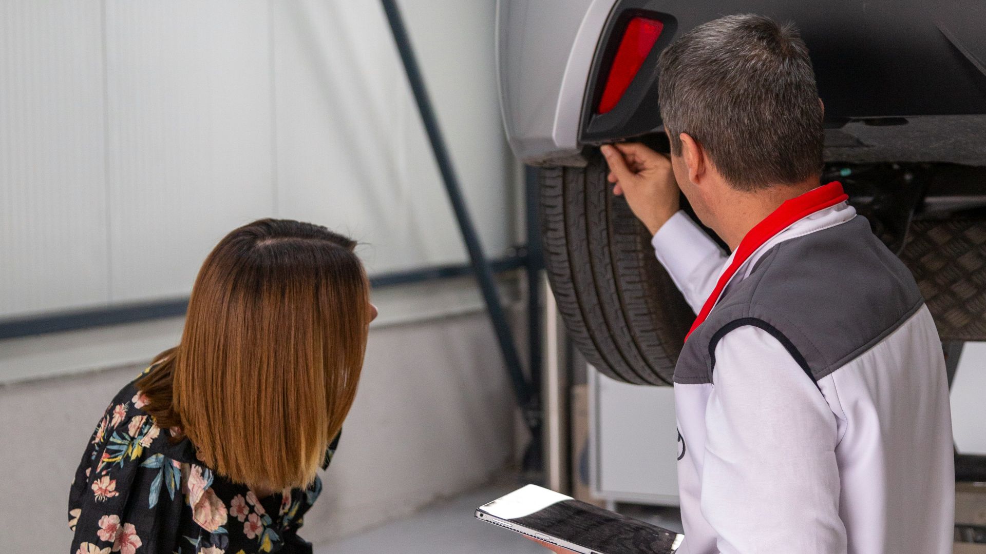 A man and a woman looking under a car