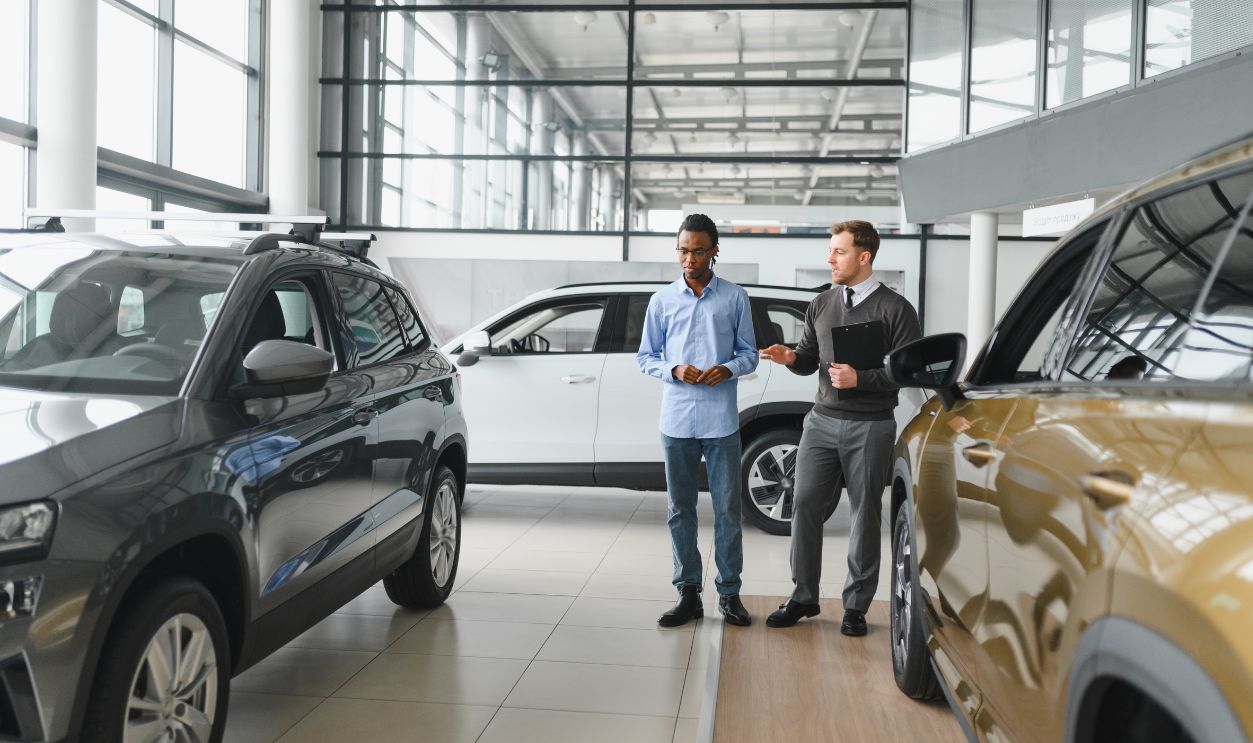 Shutterstock-2630961627, Portrait of male client talking to professional car dealer in dealership. Concept of choosing and buying new auto.