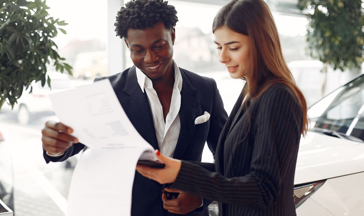 Business professionals discussing documents at a car dealership