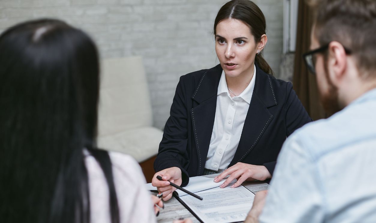 Three colleagues engaged in a business meeting discussing documents at a table indoors